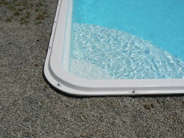 Le bord de la piscine est en résine. On pourra fixer des lames directement dessus car il est très épais.